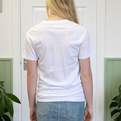 Person wearing a plain white t-shirt in front of a white door.