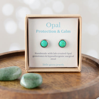Green Opal earrings on a display card with 'Opal Protection & Calm' text, placed on a wooden surface.