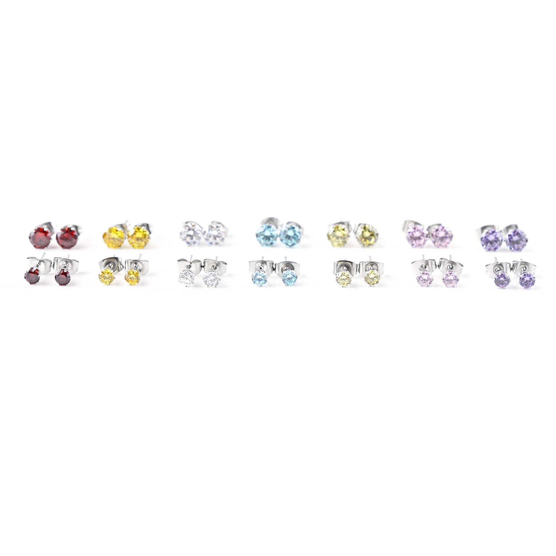 Seven different coloured CZ stud earrings in a row on white background