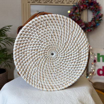 Round woven bag on a chair with a decorative wreath in the background