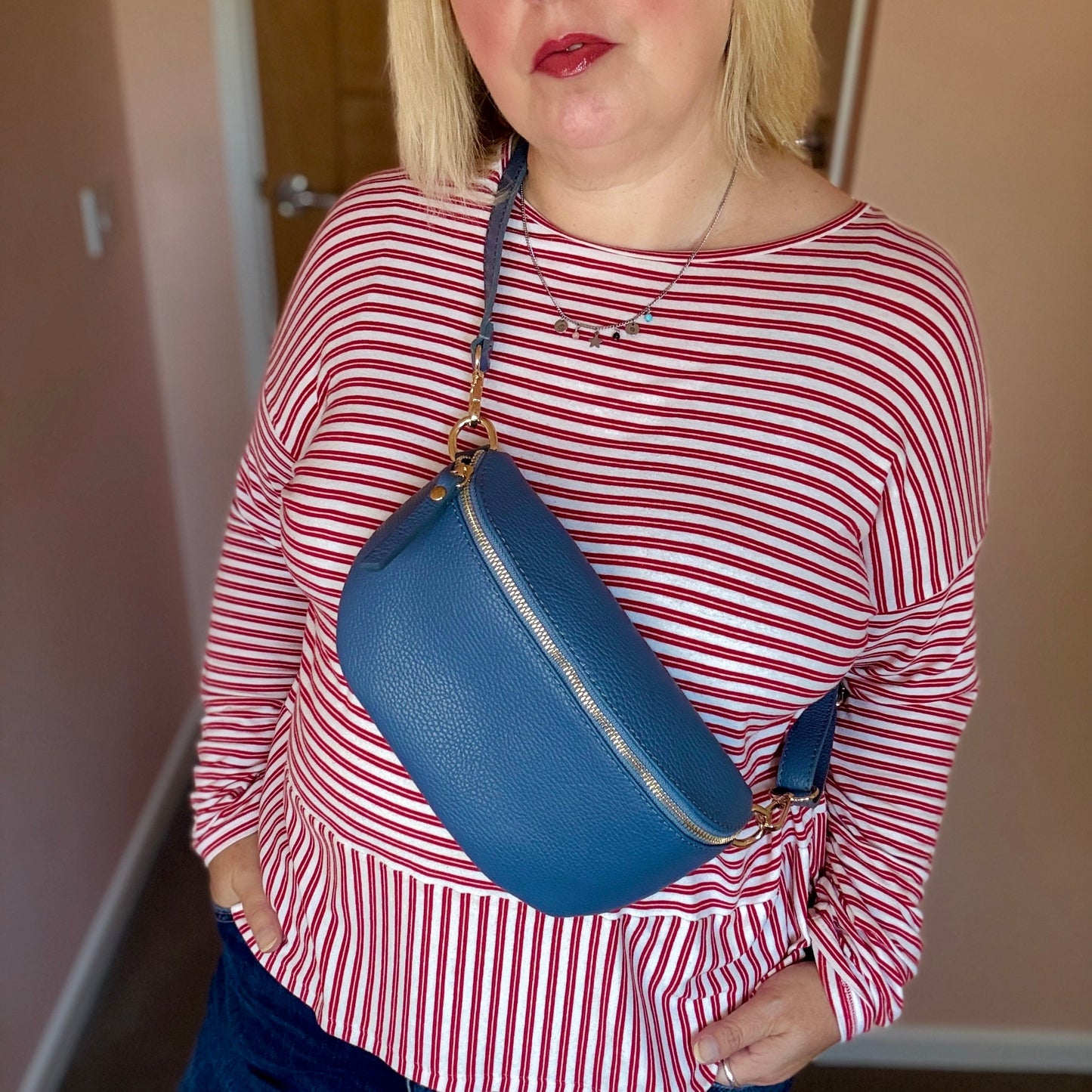 Person wearing a red and white striped shirt with a blue bag over their shoulder.