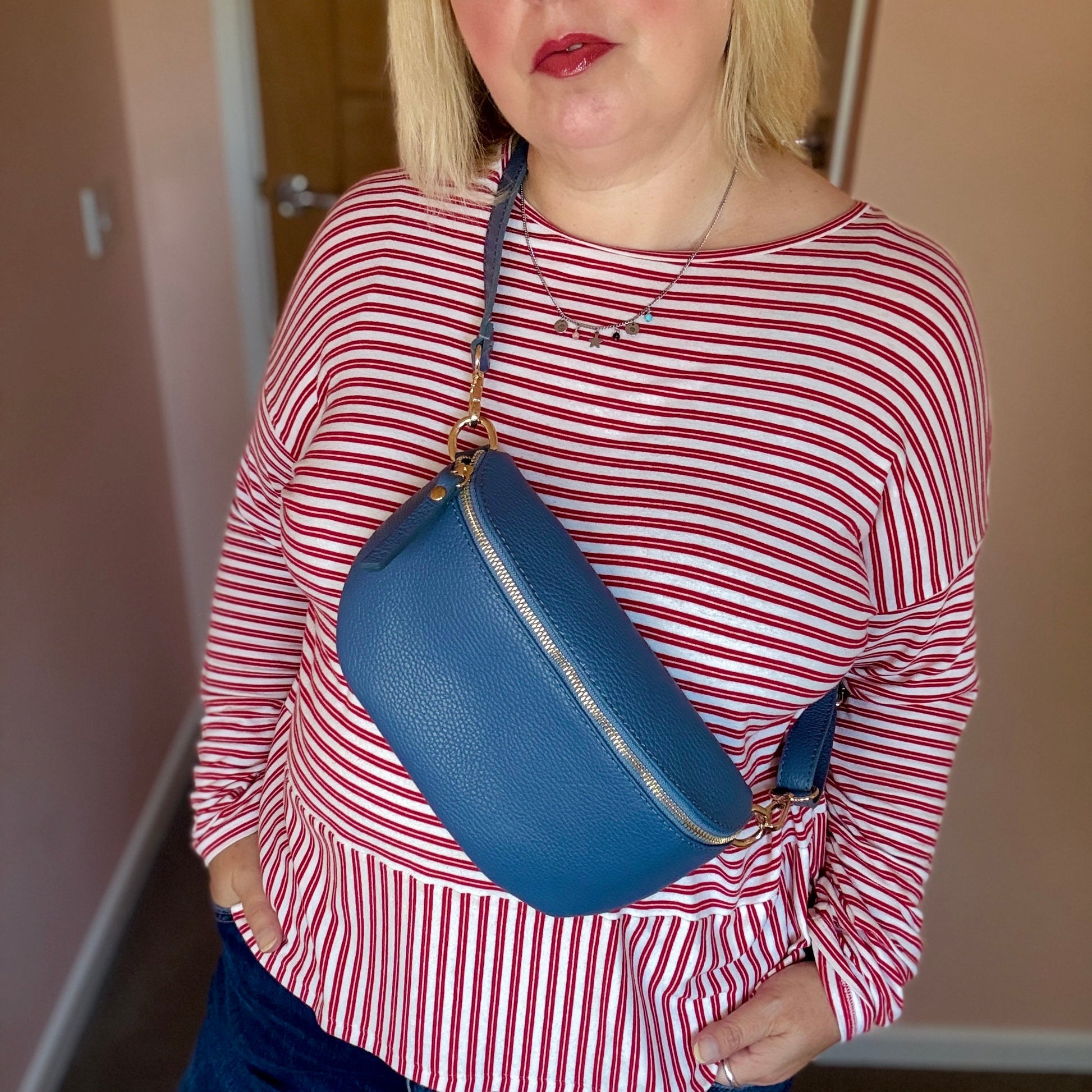 Person wearing a red and white striped shirt with a blue bag over their shoulder.