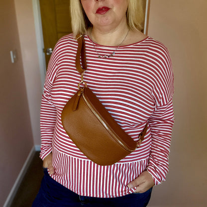 Woman wearing a red and white striped shirt holding a brown bag indoors.