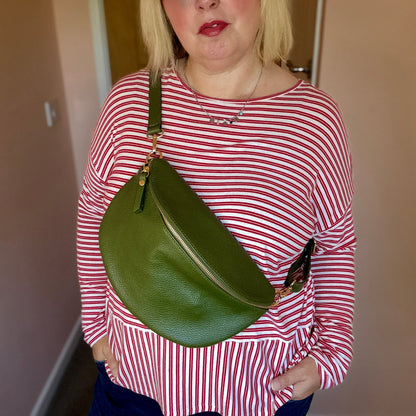 Person wearing a red and white striped shirt with a green bag, standing against a plain background.
