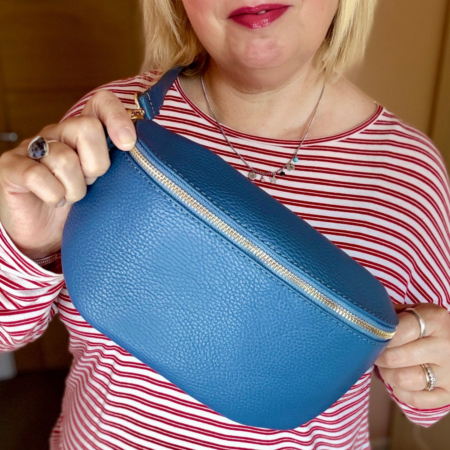 Woman holding a blue cylindrical pouch against a neutral background