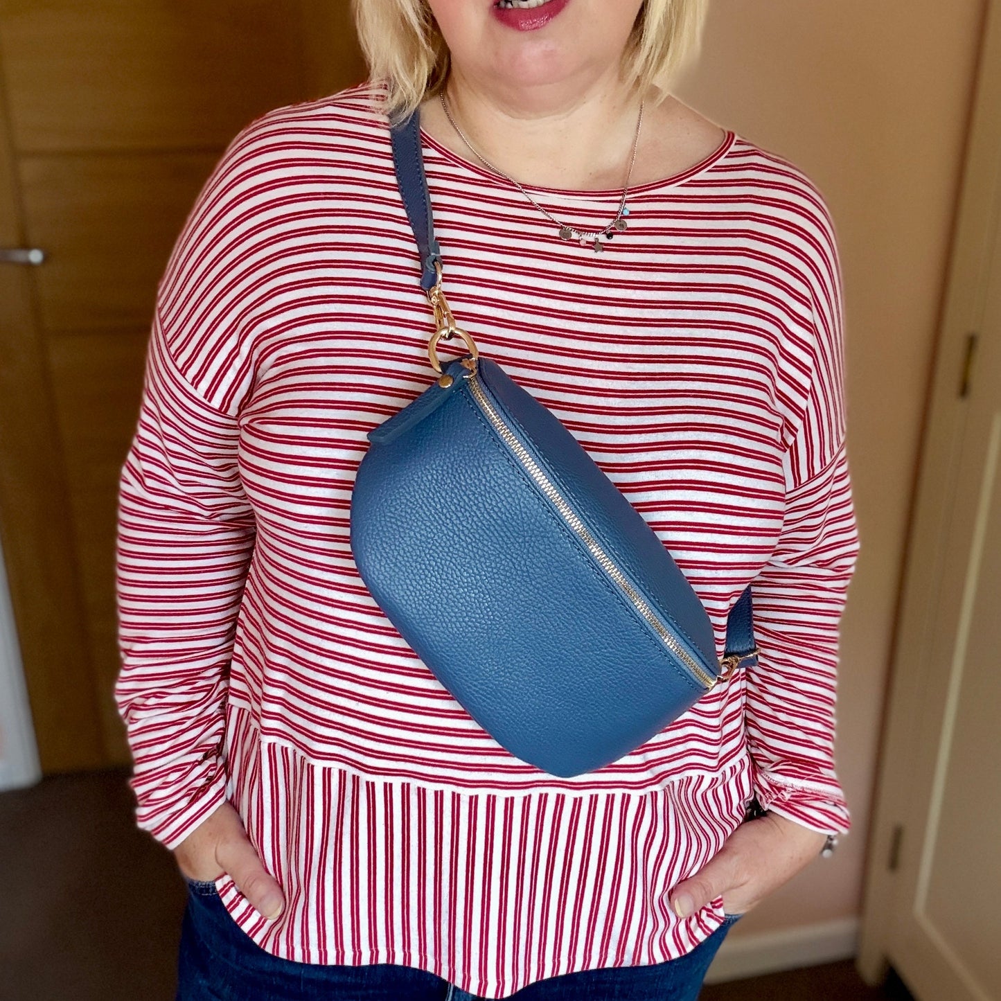 Woman wearing a red and white striped shirt with a blue bag, standing indoors.