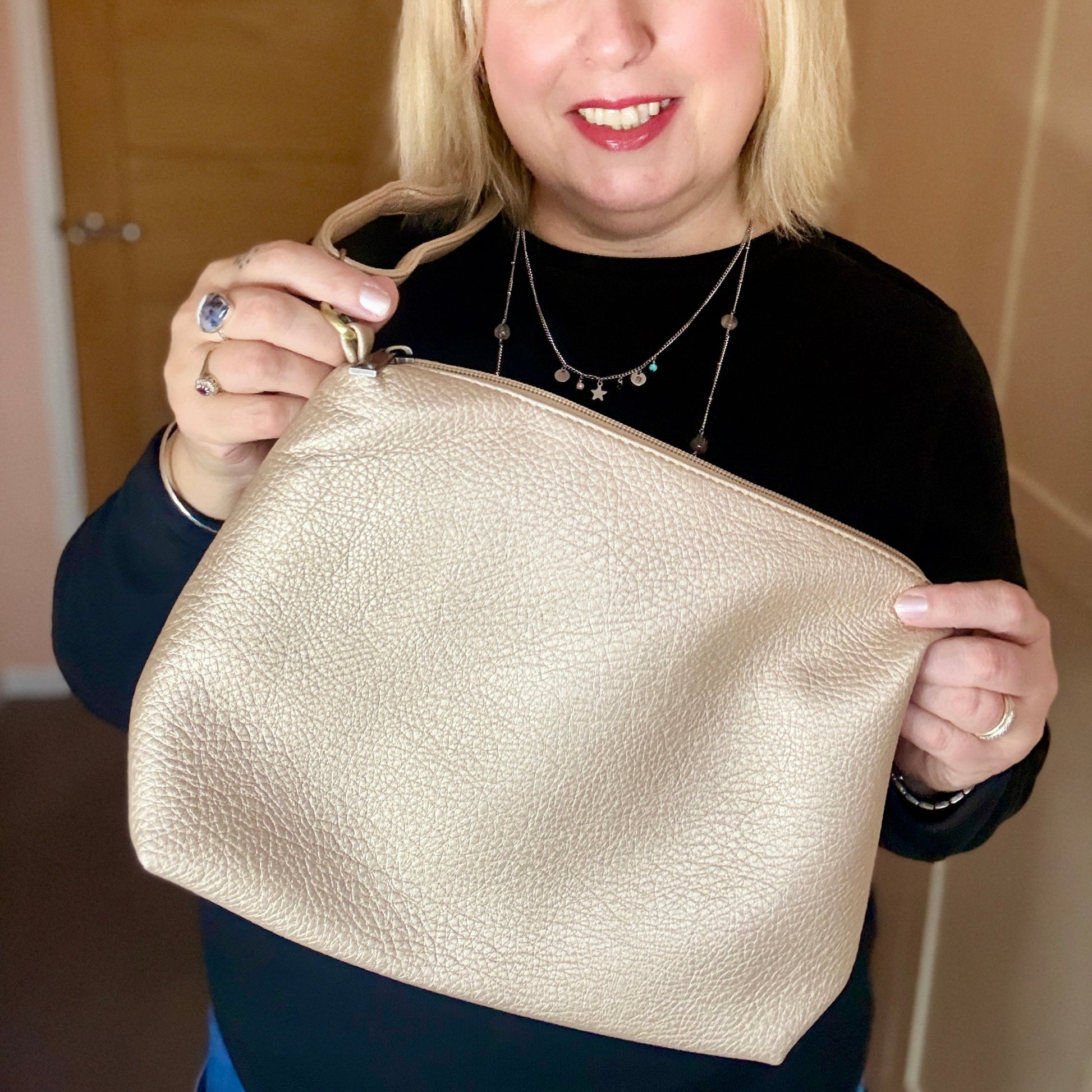 Woman holding a gold clutch bag indoors