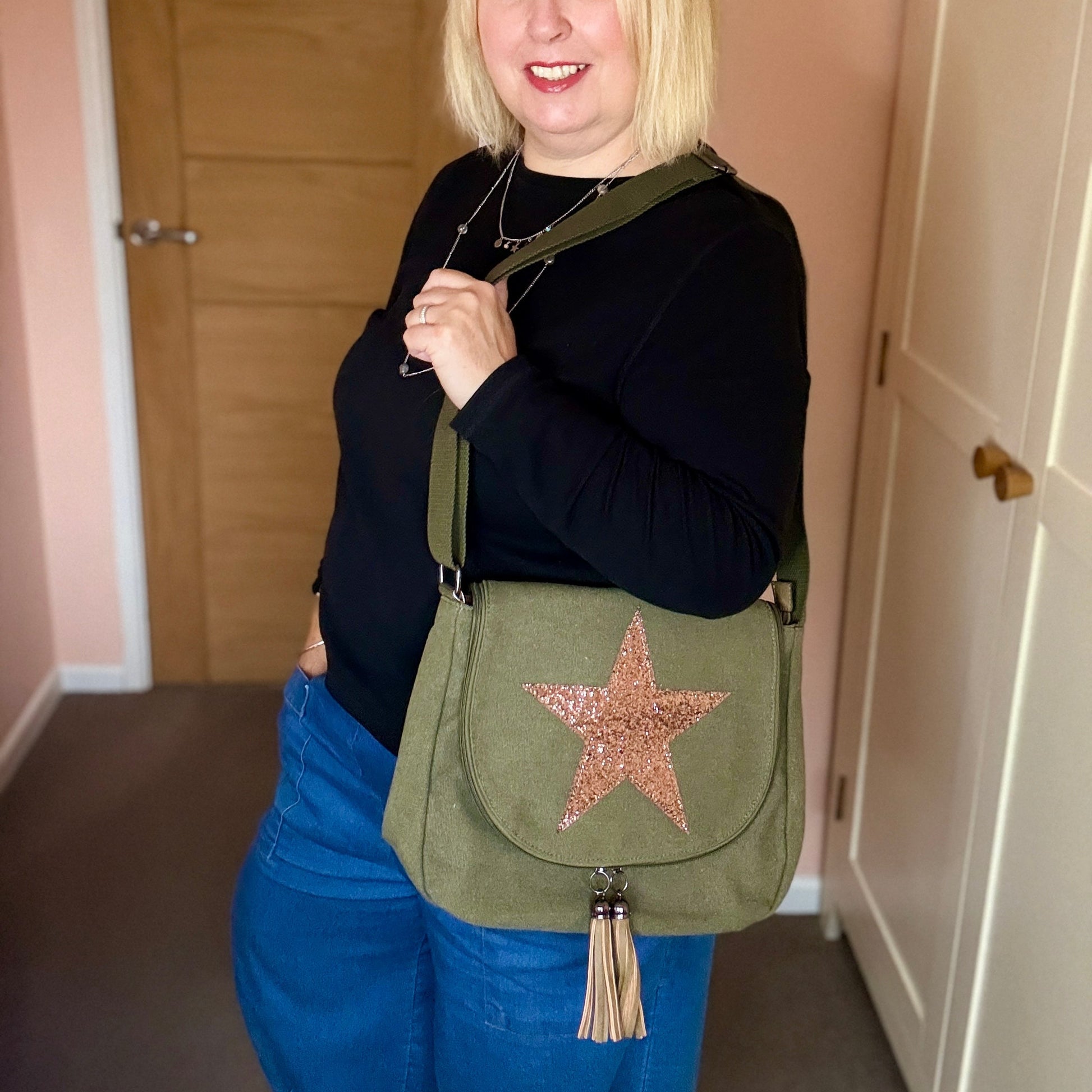 Woman holding a green bag with a star design in a room.