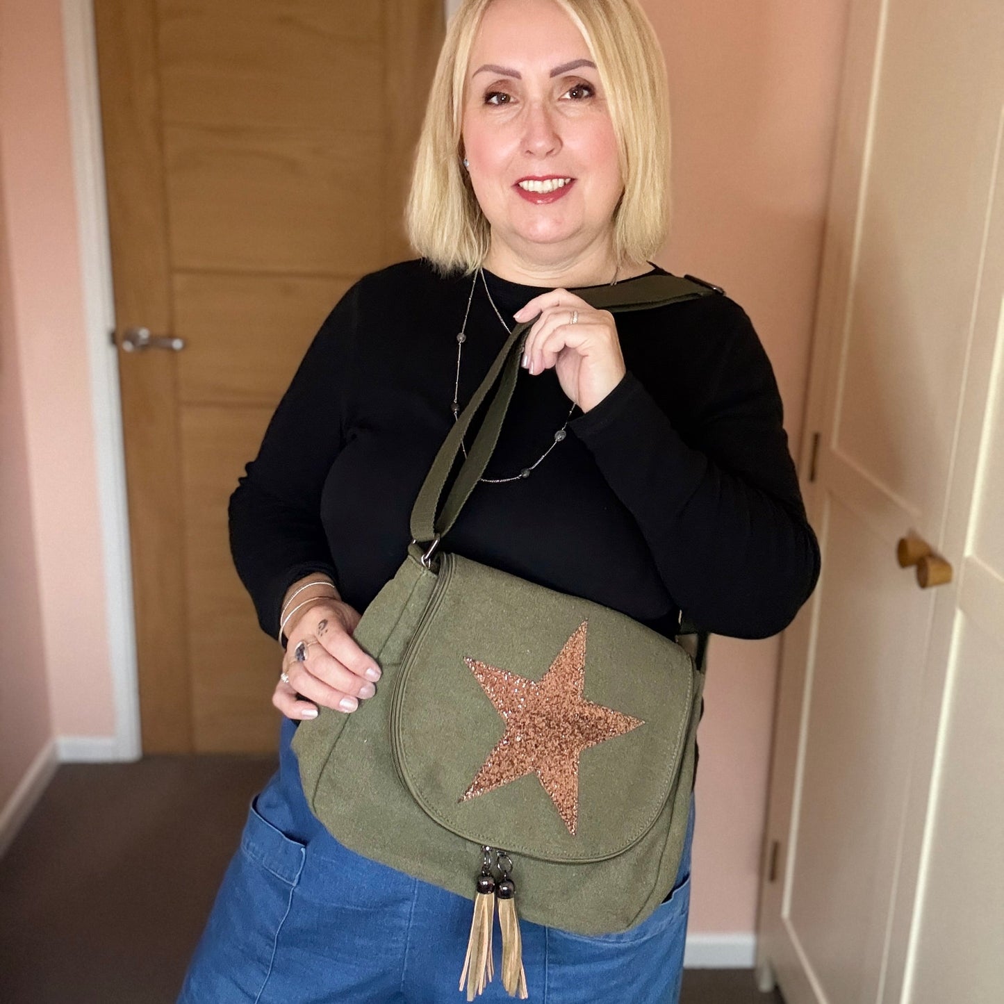 Woman holding a green bag with a star design indoors.