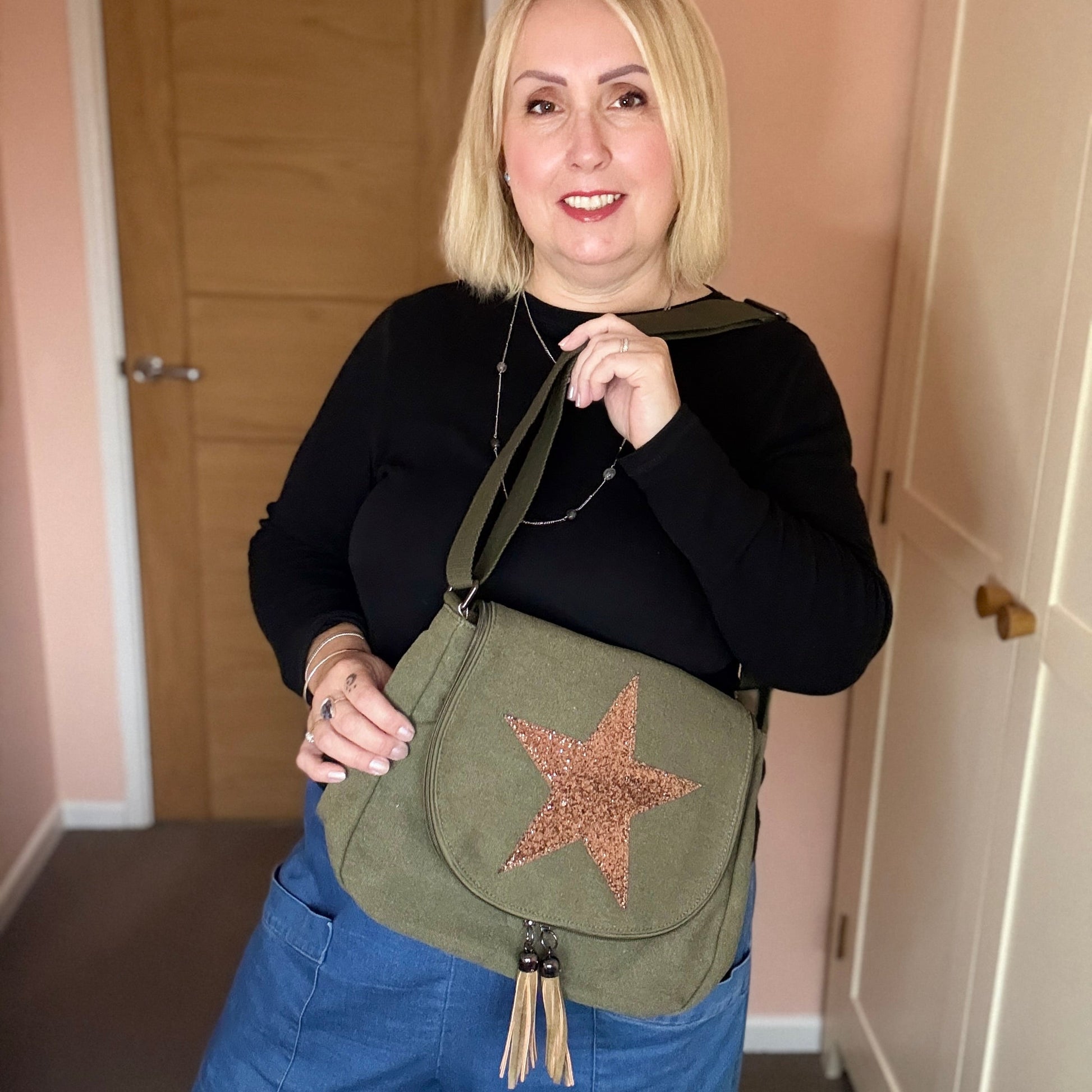 Woman holding a green bag with a star design indoors.