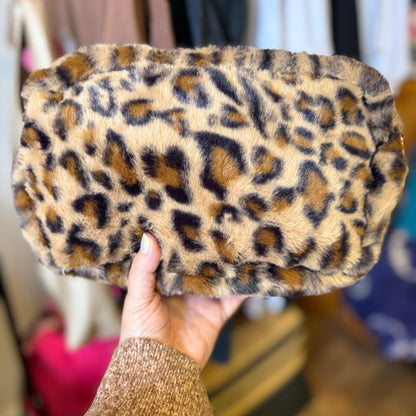 Leopard print clutch held by a hand with a blurred background
