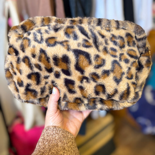 Leopard print clutch held by a hand with a blurred background