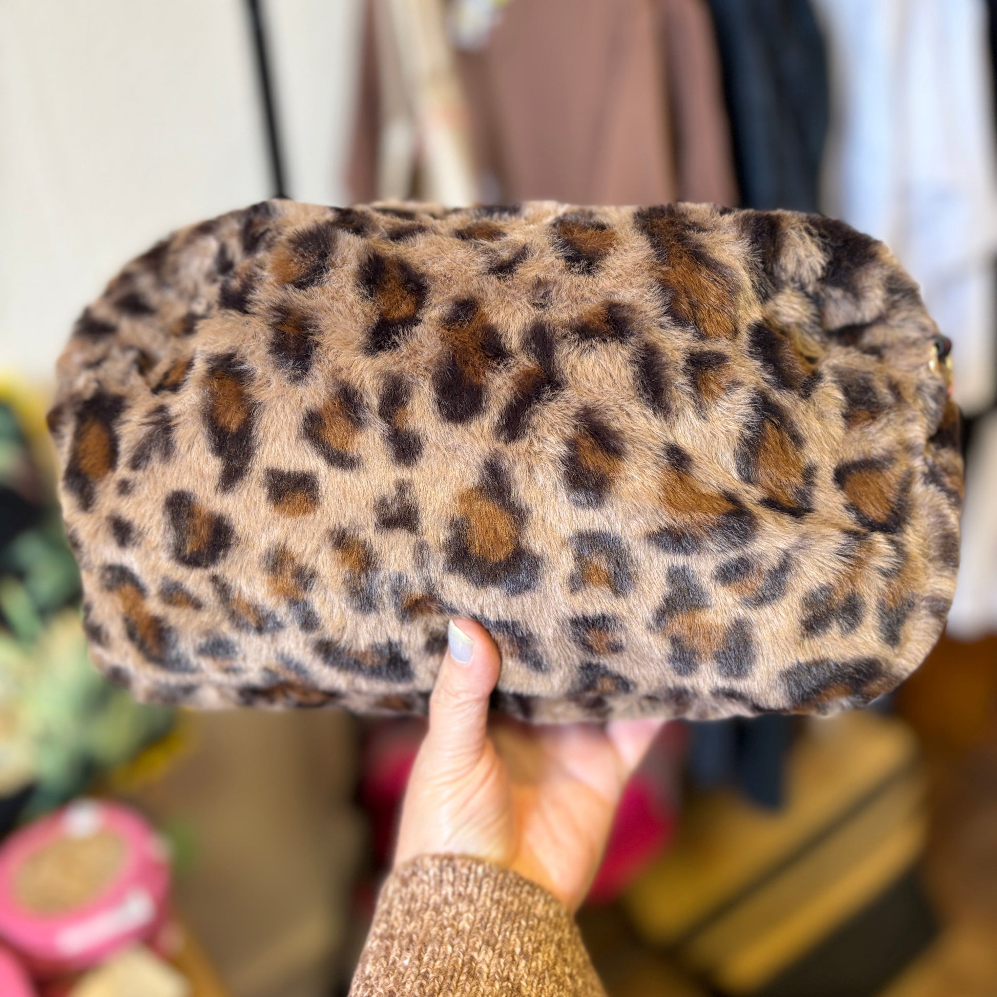 Leopard print clutch held by a person with a blurred background