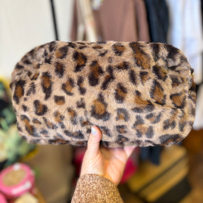 Leopard print clutch held by a person with a blurred background