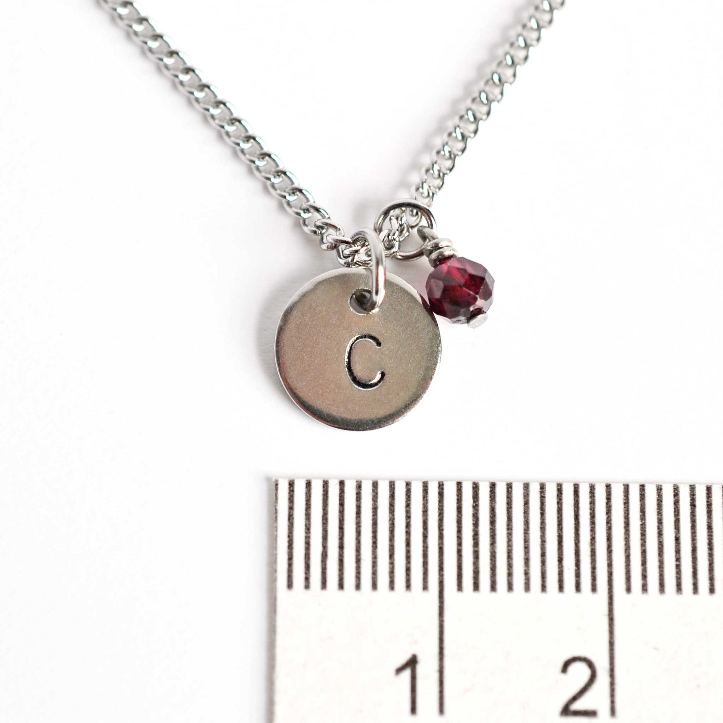 1cm diameter round steel pendant with hand stamped initial and 4mm January birthstone charm