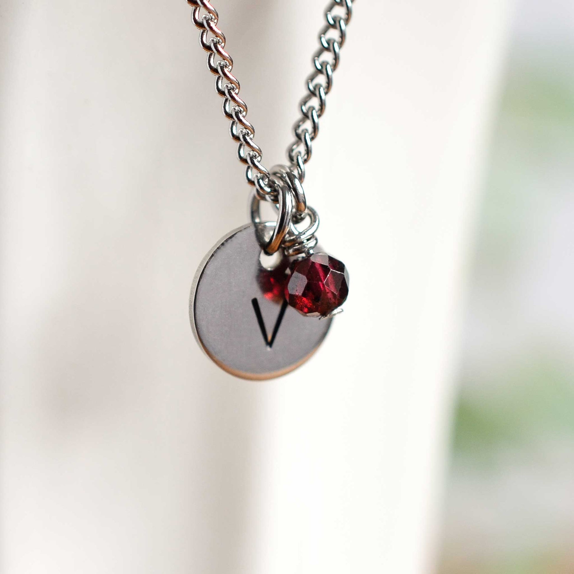 Close up of letter V initial pendant with Garnet January birthstone charm