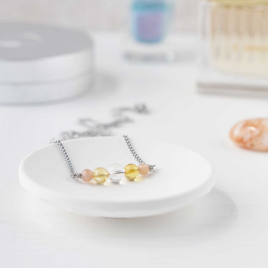 Dainty yellow gemstone necklace in trinket dish on dressing table