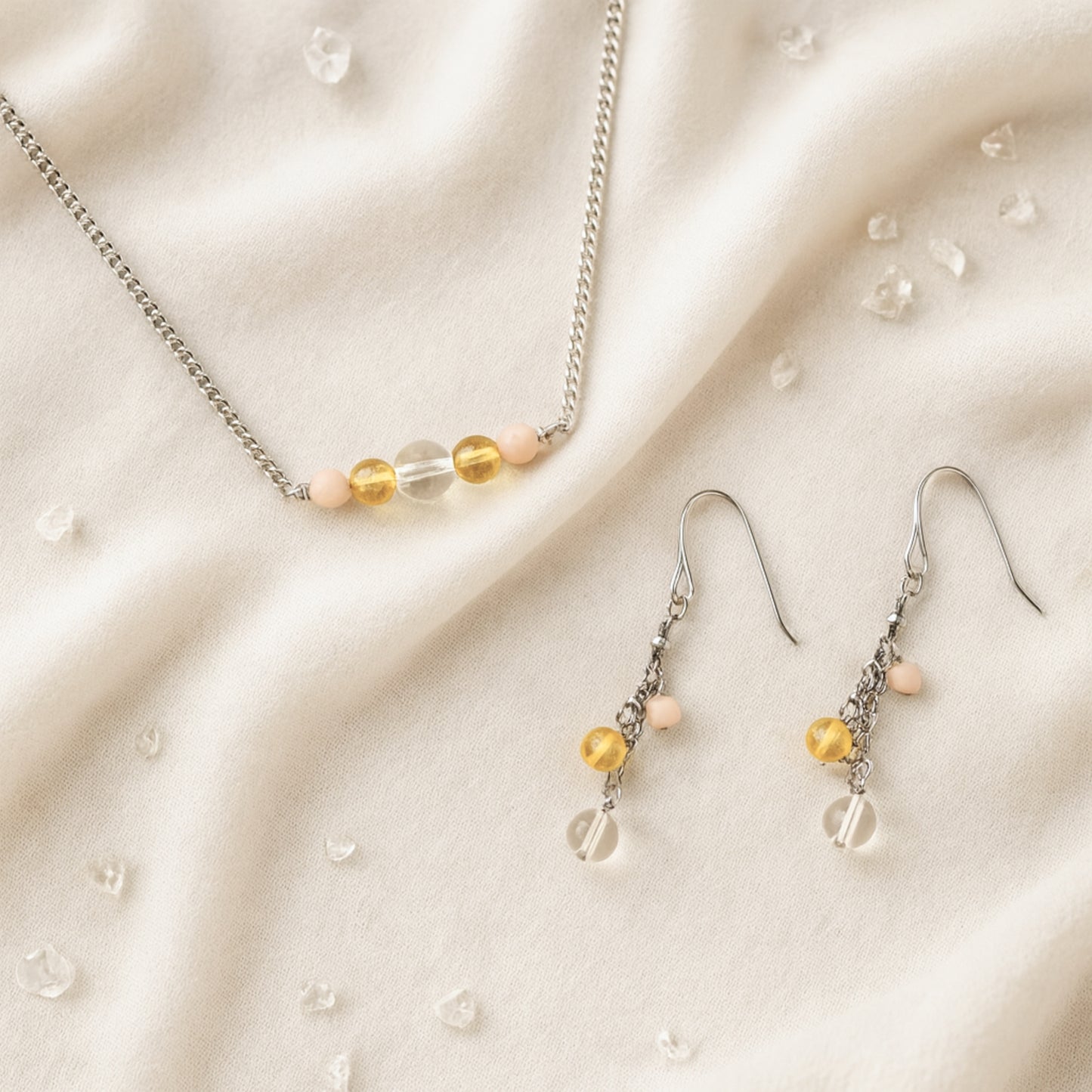 Necklace and earrings with yellow gemstone beads on a beige fabric background