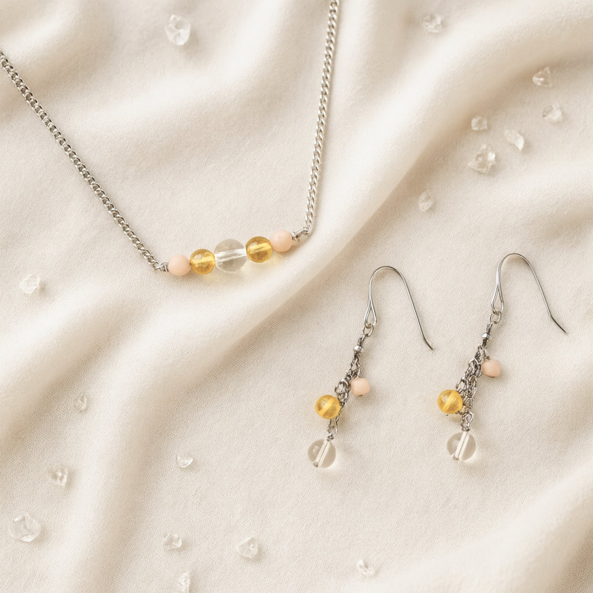 Necklace and earrings with yellow gemstone beads on a beige fabric background