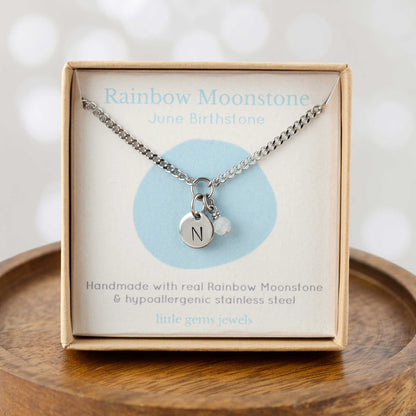 Rainbow Moonstone June Birthstone necklace with hand stamped initial inside an eco-friendly gift box sitting on wooden coaster