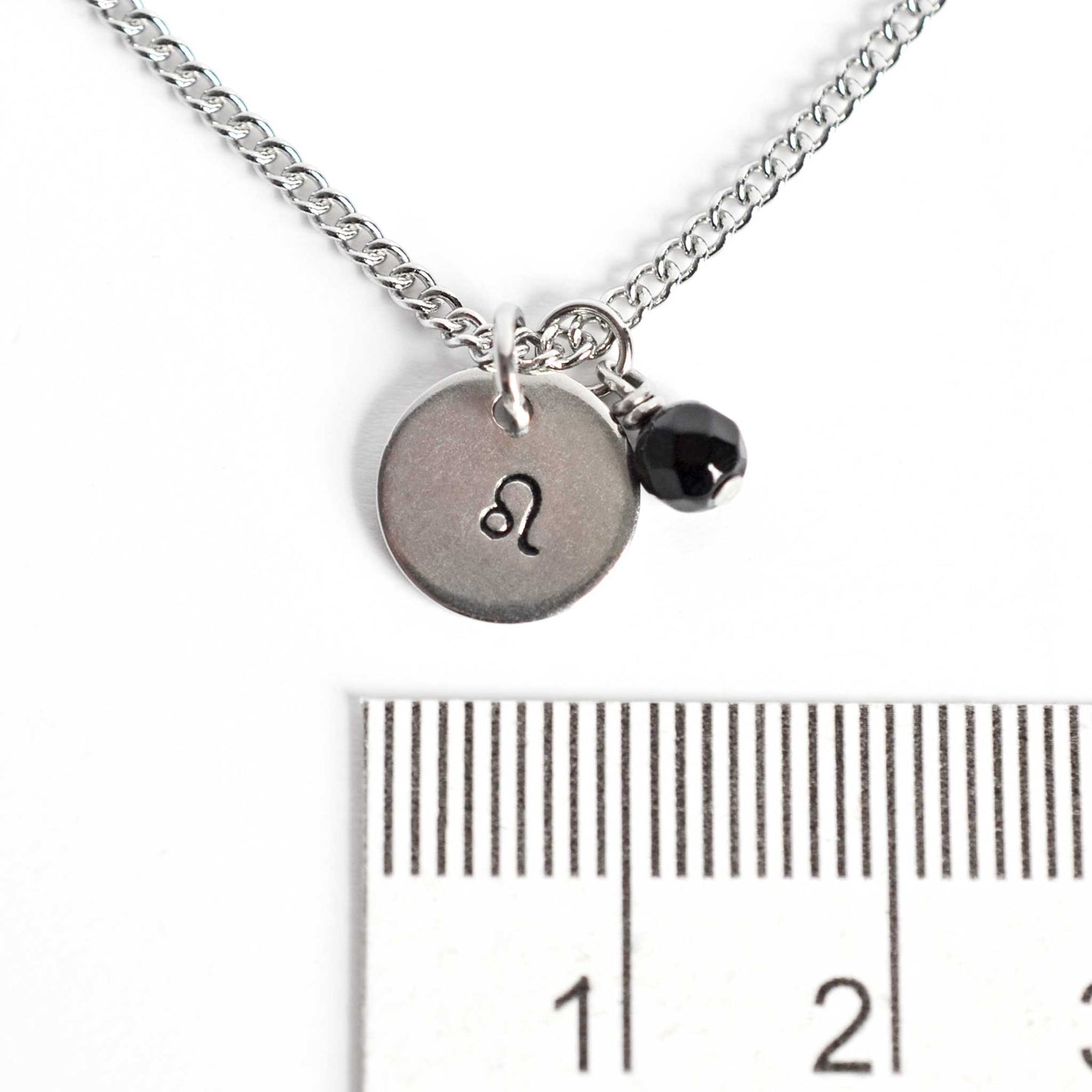 1cm diameter disc pendant with hand stamped Leo zodiac sign and 4mm Onyx gemstone charm