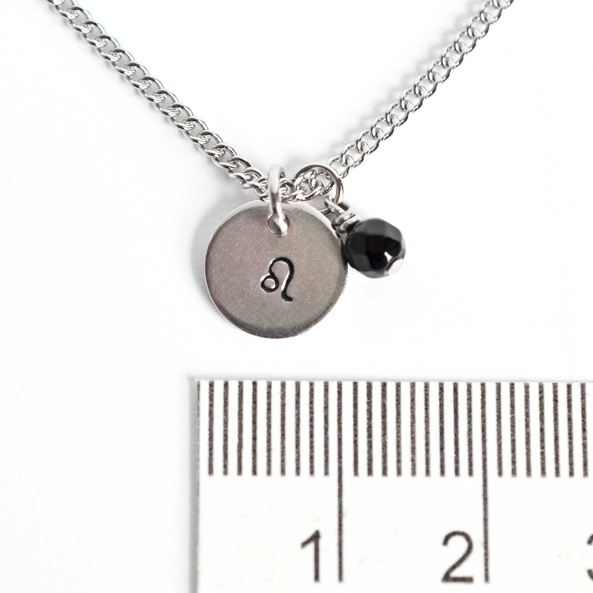 1cm diameter disc pendant with hand stamped Leo zodiac sign and 4mm Onyx gemstone charm