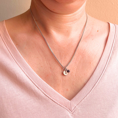 Woman wearing a pink v neck top and dainty Leo zodiac sign necklace.