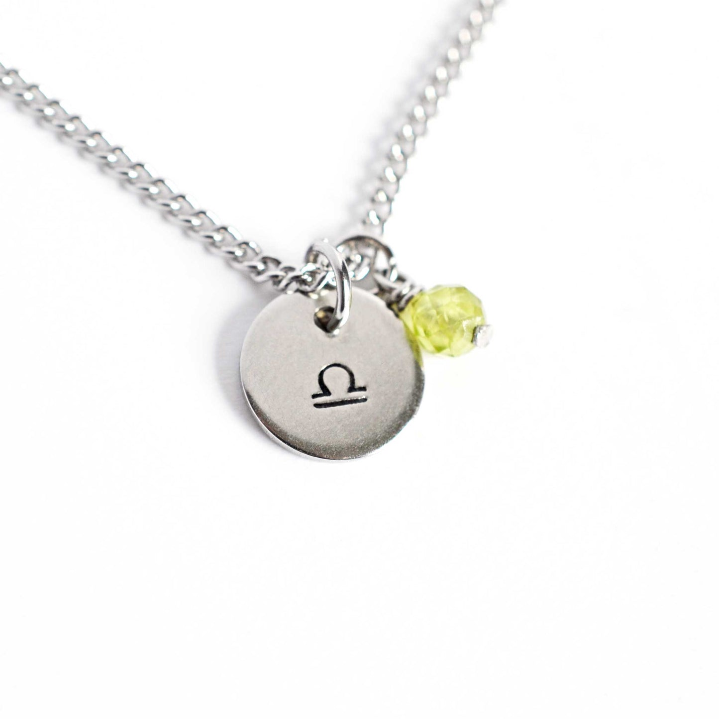 Libra Zodiac pendant necklace with tiny Peridot gemstone charm on white background