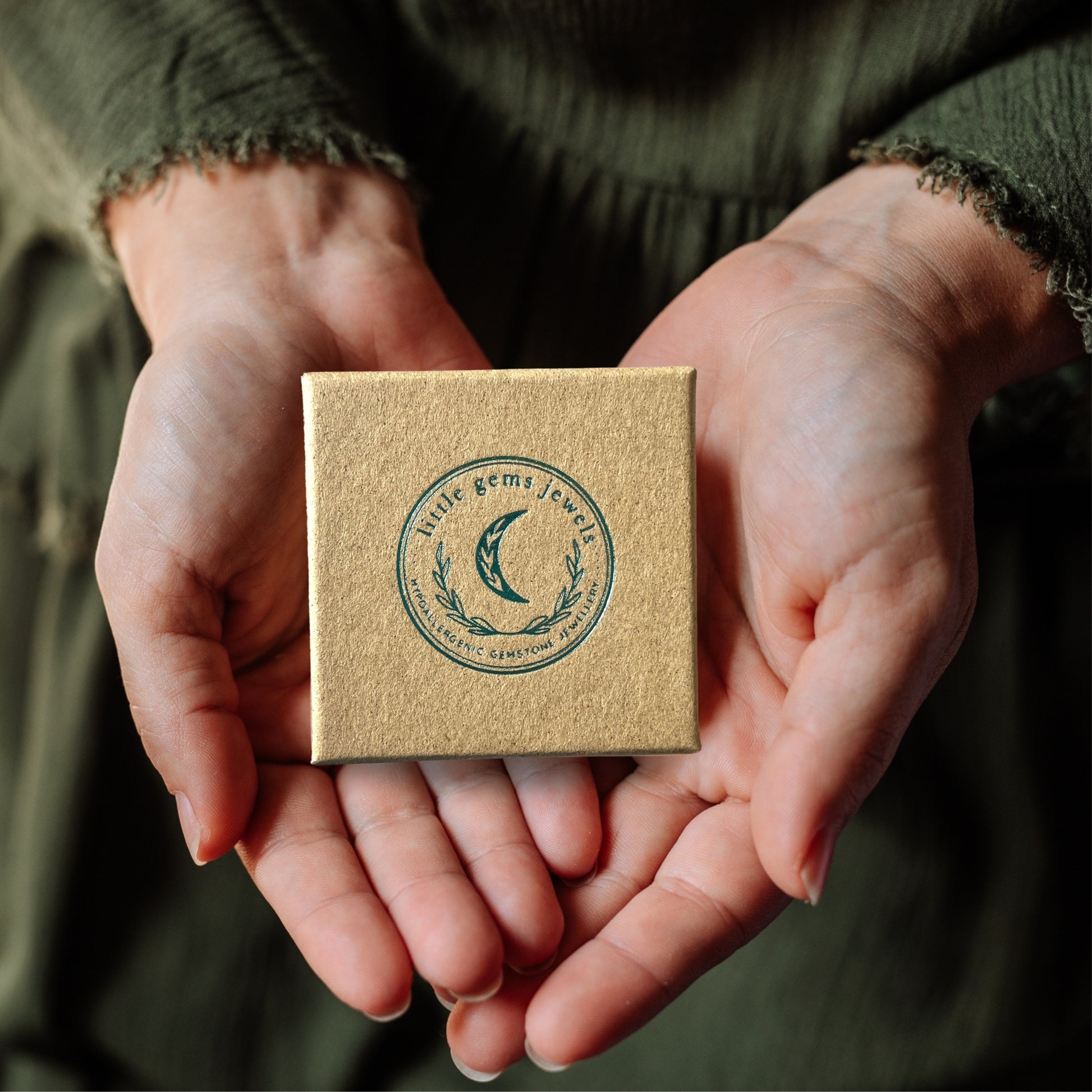 Eco jewellery box with a logo held in hands against a blurred background
