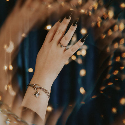Hand with a ring and bracelet against a blurred background of lights
