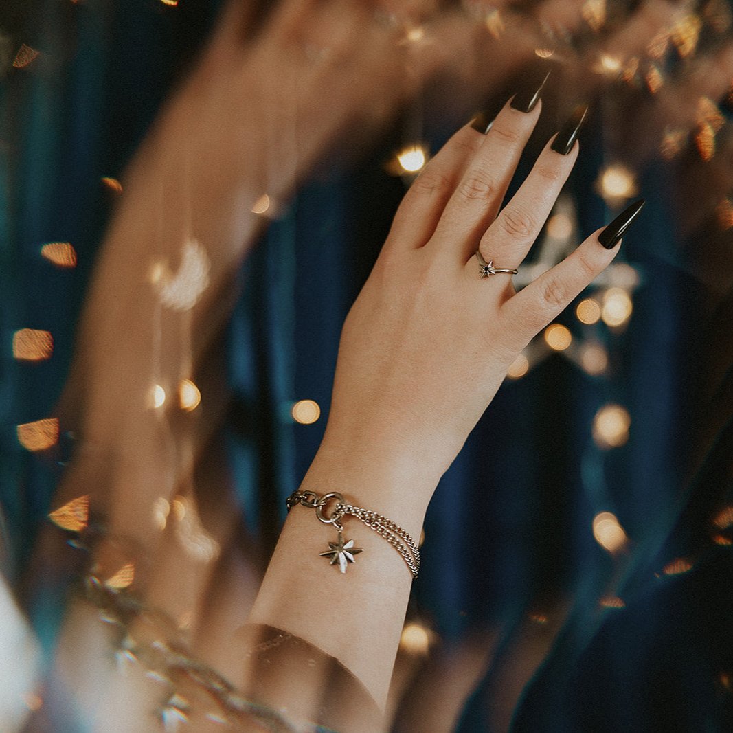 Hand with a ring and bracelet against a blurred background of lights