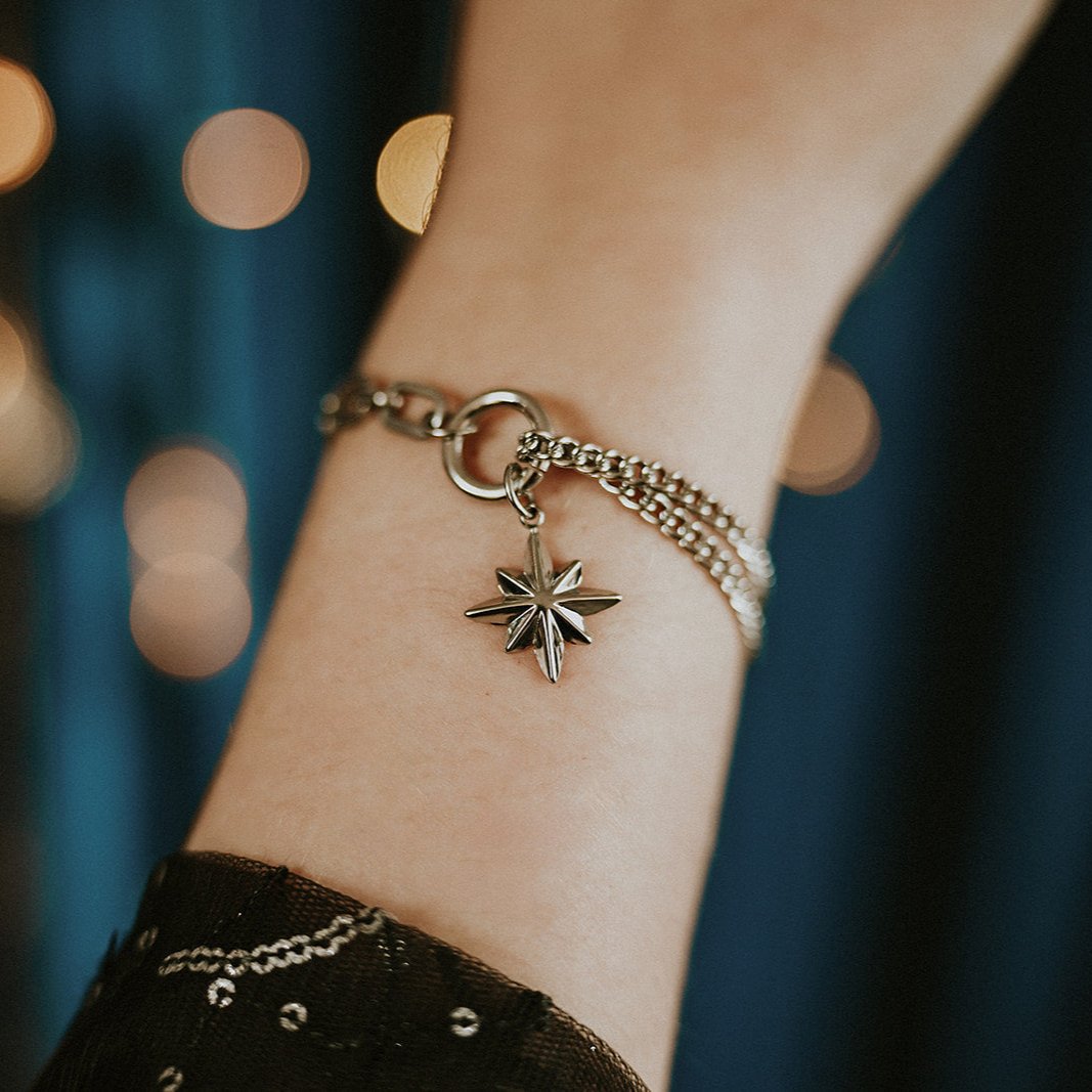 Bracelet with a star-shaped charm on a wrist against a blurred background