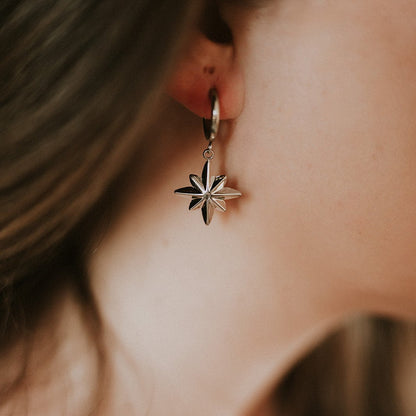 Close-up of a person wearing a silver star-shaped earring.