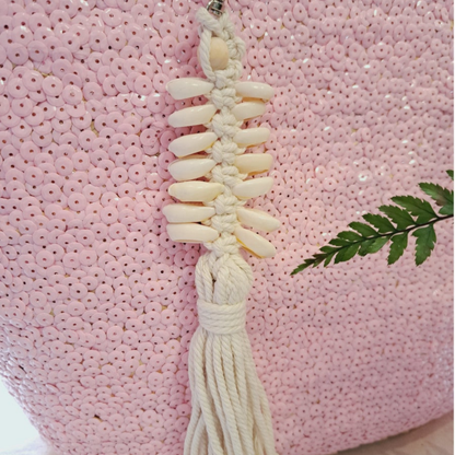 Shell handbag charm on a pink textured background