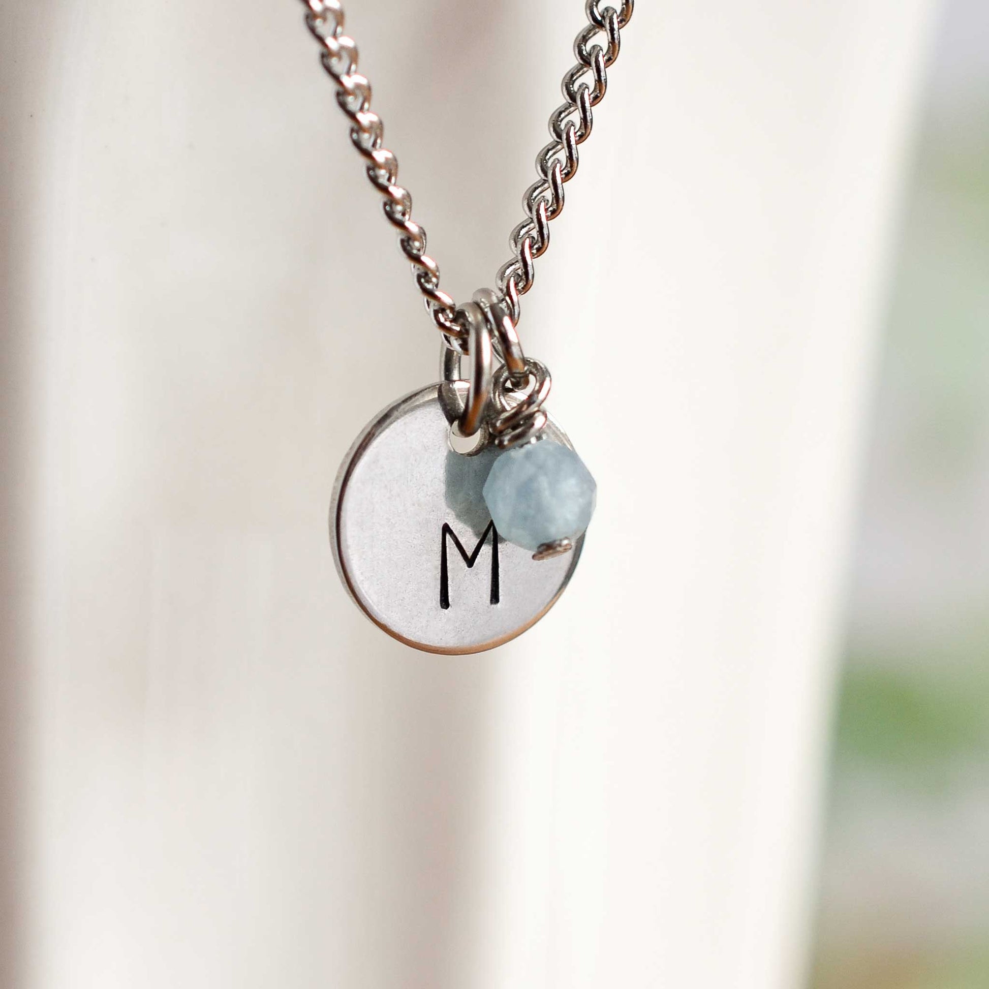 Close up of initial M letter pendant with Aquamarine March birthstone charm