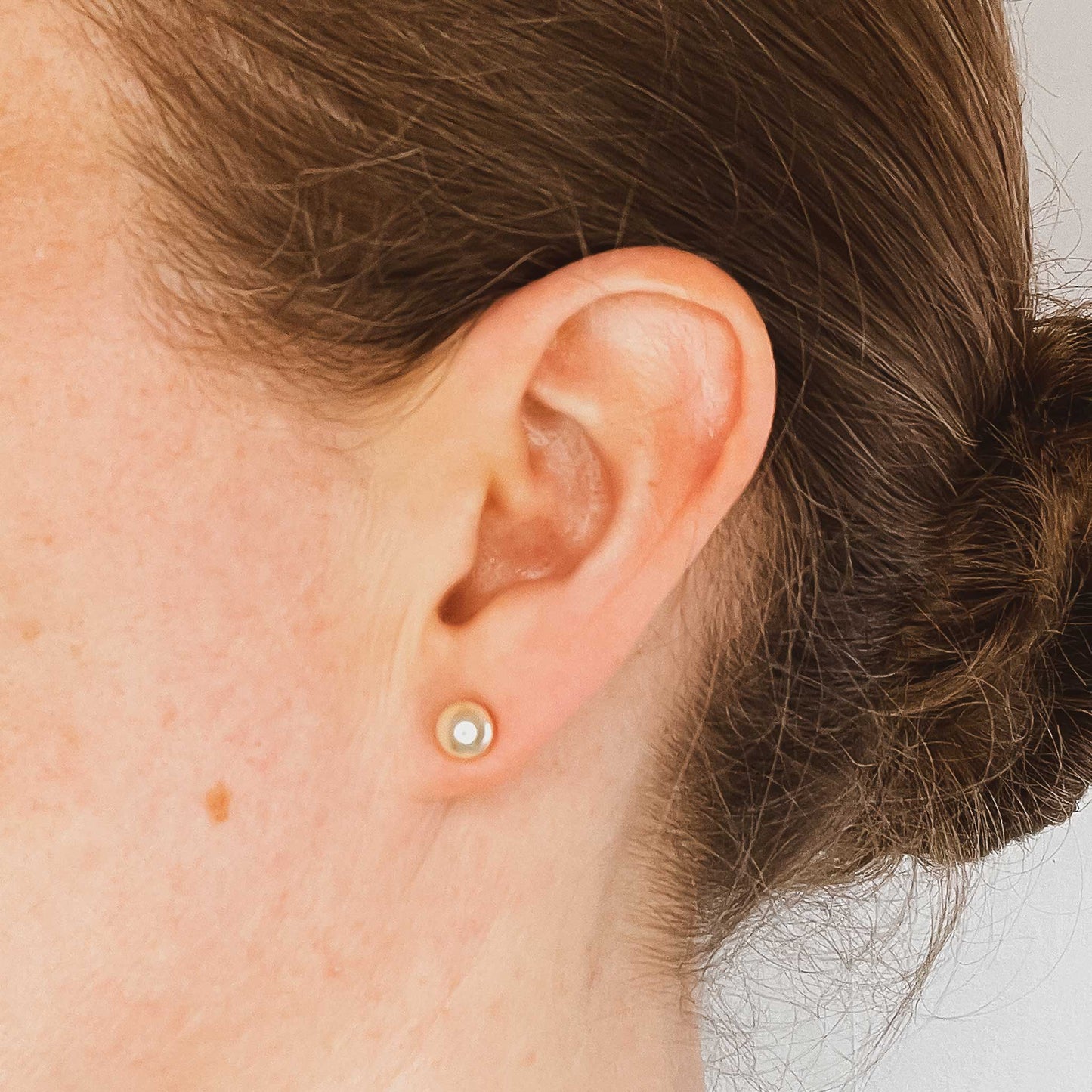 Woman wearing 6mm faux pearl stud earring in earlobe