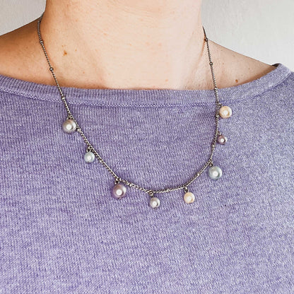 Woman wearing purple jumper and faux pearl charms necklace
