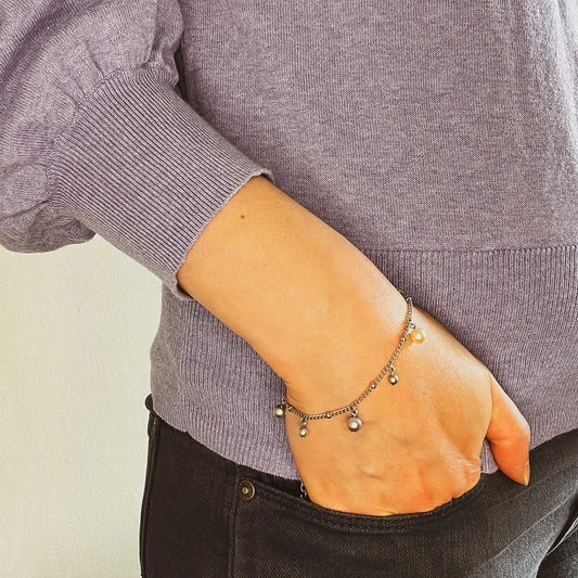 Woman wearing purple jumper and dainty faux pearl charms bracelet