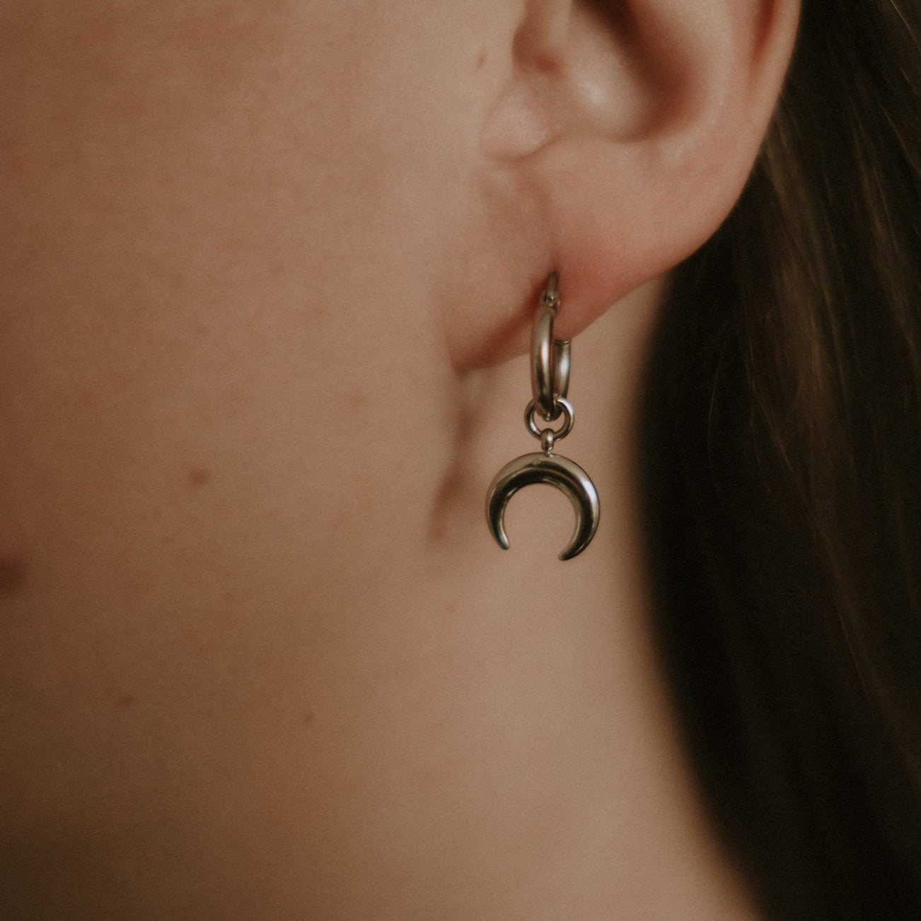 Steel crescent moon earring worn by a person