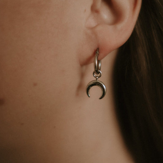 Steel crescent moon earring worn by a person