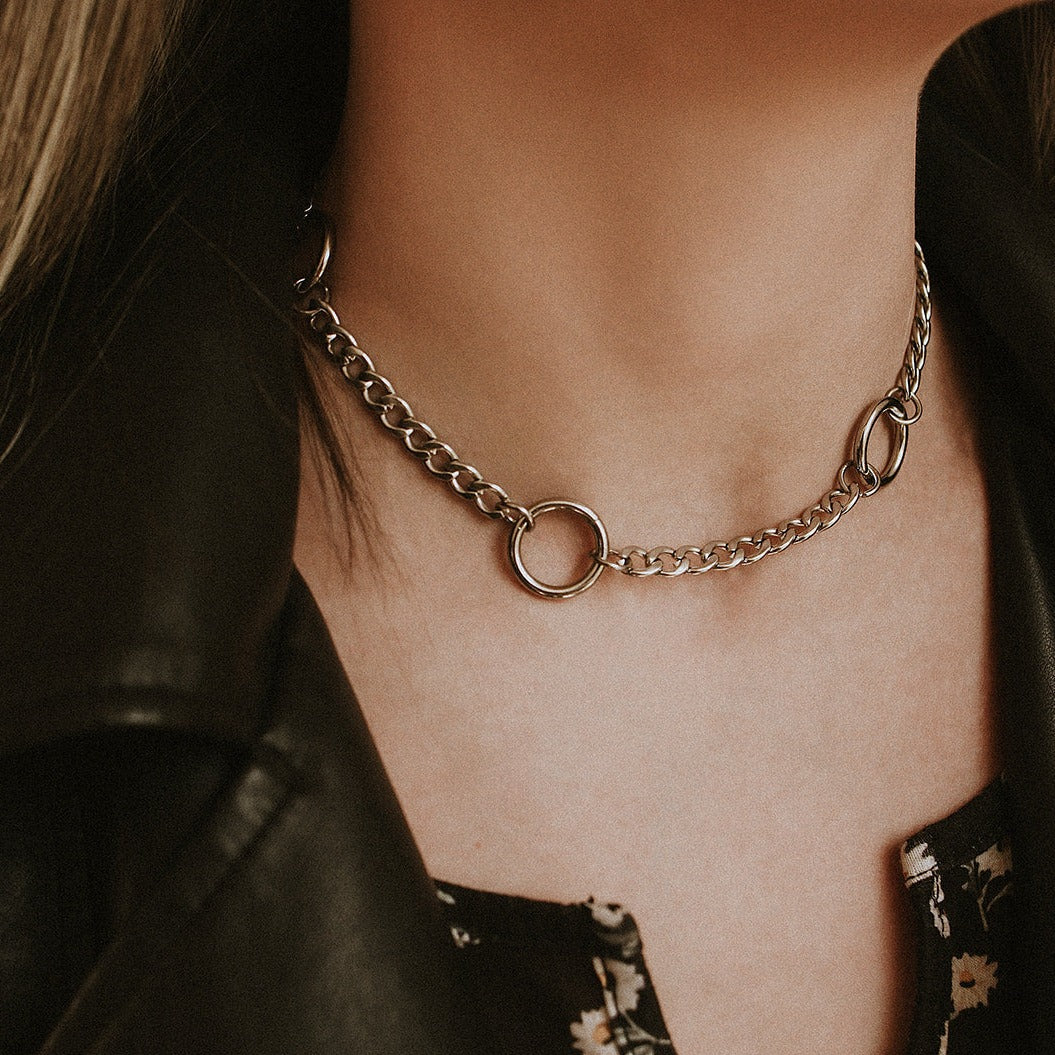 Close-up of a chain necklace on a person wearing a black leather jacket.