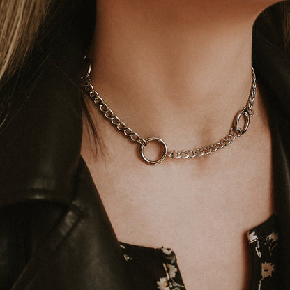 Close-up of a chain necklace on a person wearing a black leather jacket.