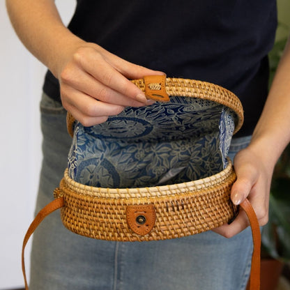 Person holding a woven handbag with floral patterned interior