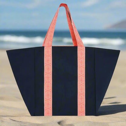 Blue tote bag with red handles on a sandy beach