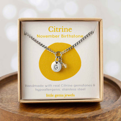 Citrine November Birthstone necklace with hand stamped initial inside an eco-friendly gift box sitting on wooden coaster