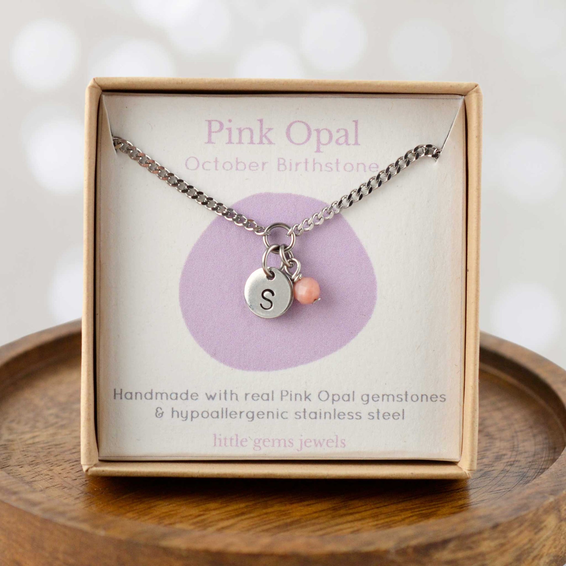 Pink Opal October Birthstone necklace with hand stamped initial inside an eco-friendly gift box sitting on wooden coaster