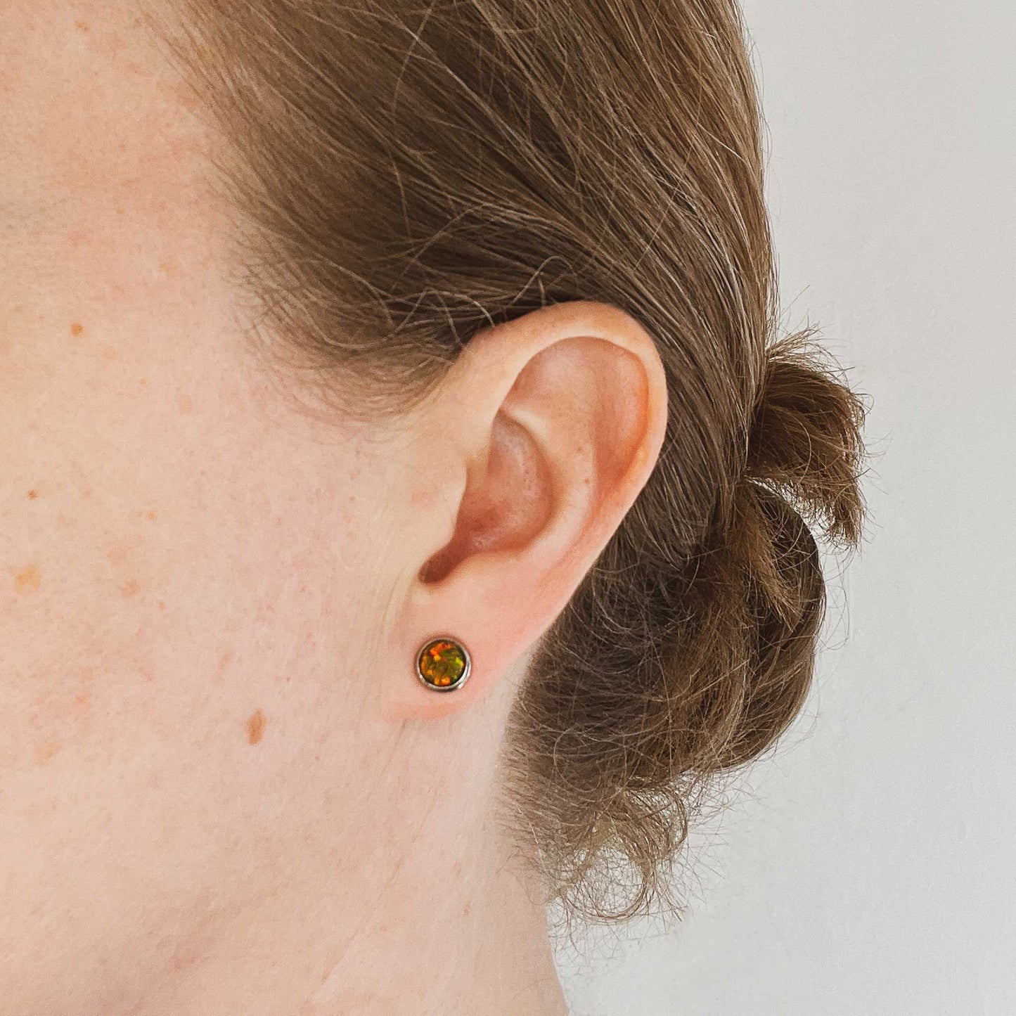 Woman wearing dark green Opal stud earring in earlobe
