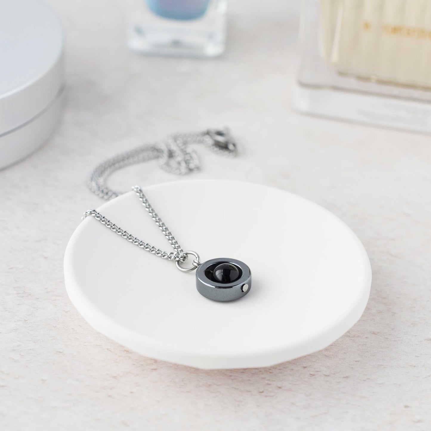 Dainty gemstone spinner necklace on white trinket dish.