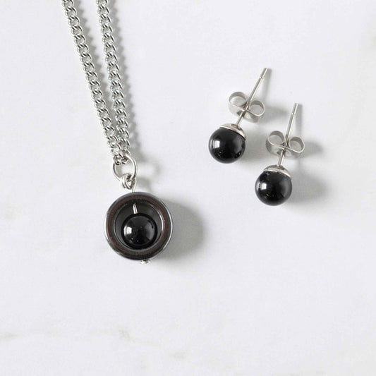 Matching Onyx spinner necklace and stud arrings on a white marble background.