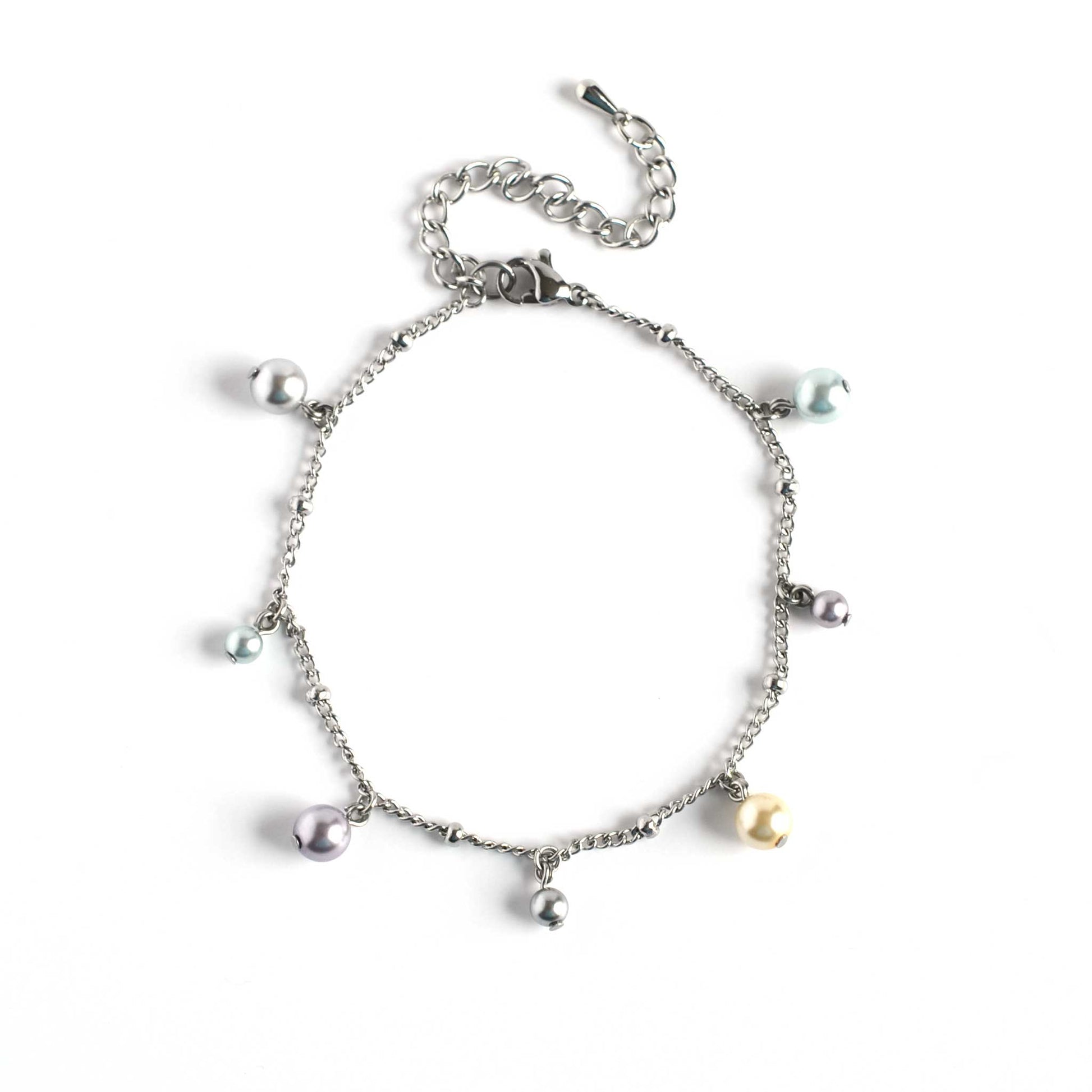 Flat lay of adjustable faux pearl charms bracelet on white background
